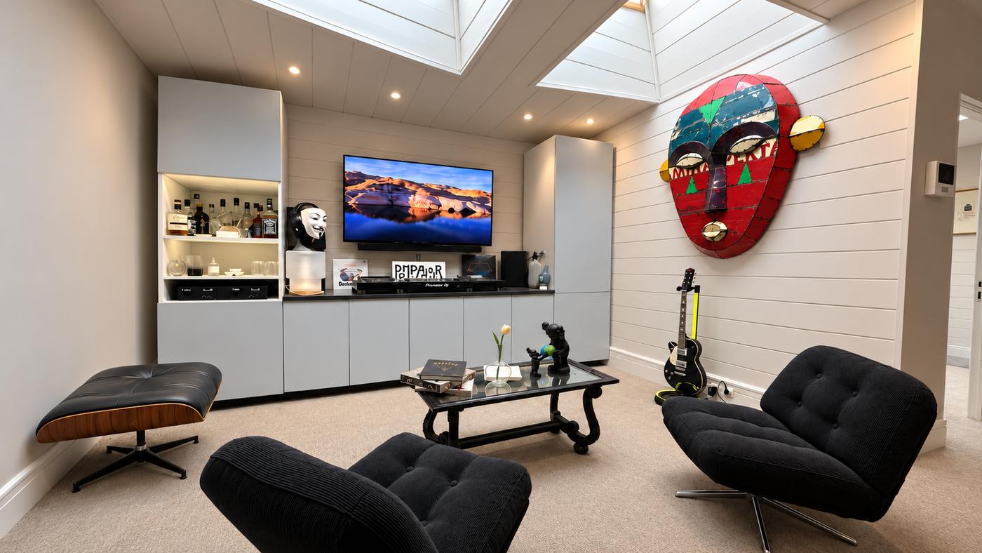 Lounge of the agency's offices: Pioneer DJ decks on a low unit, wall-mounted screen, lit bar and black armchairs under skylights.