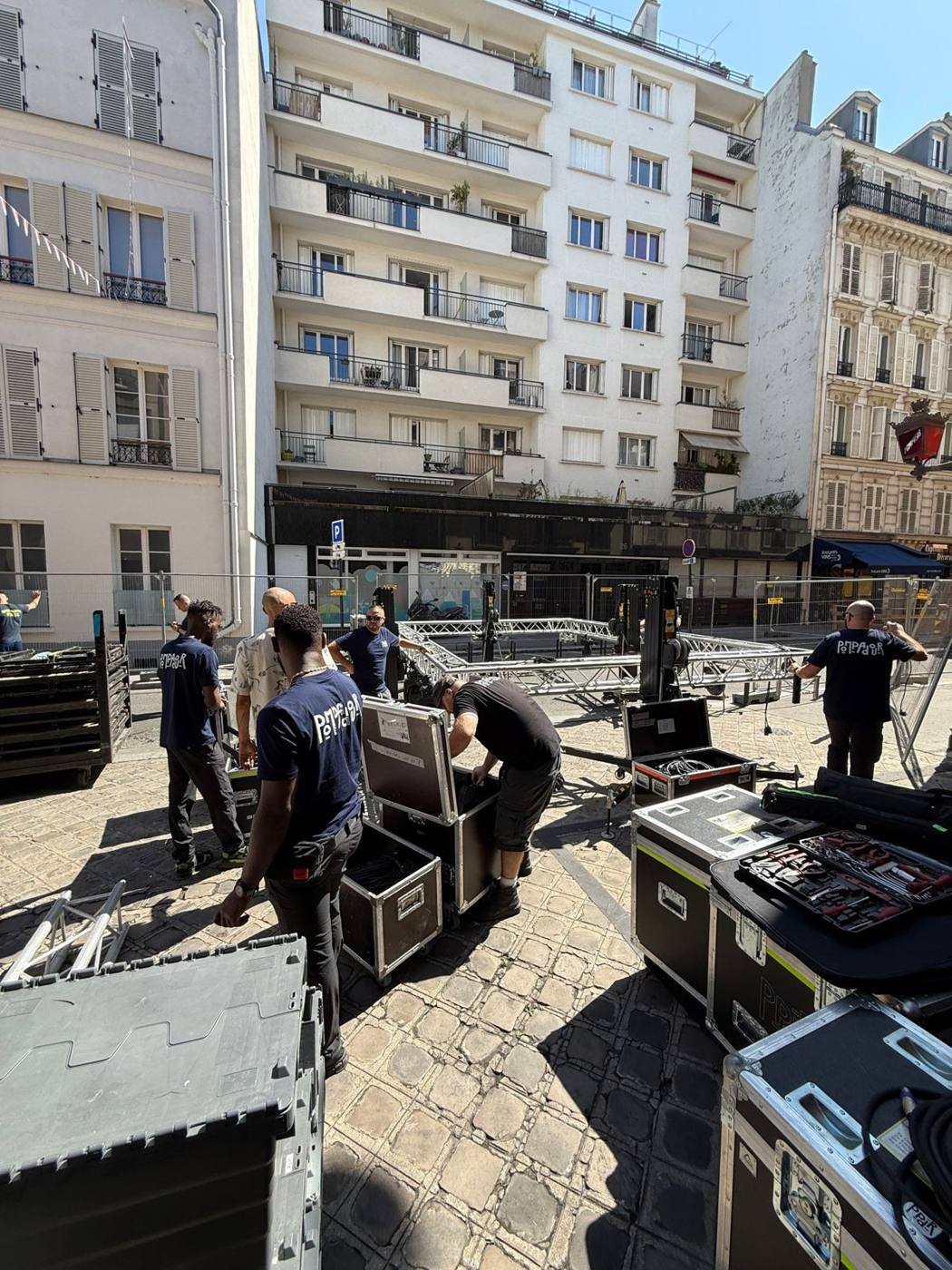 Flight cases ouverts sur les pavés pendant le montage de la scène.