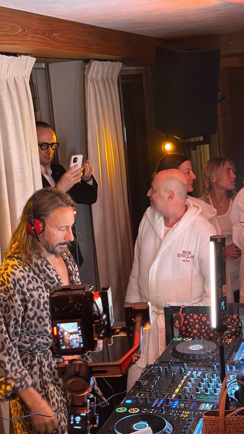 DJ au casque rouge en peignoir léopard, invités en peignoirs blancs Bob Sinclar × Brach, caméra sur stabilisateur.