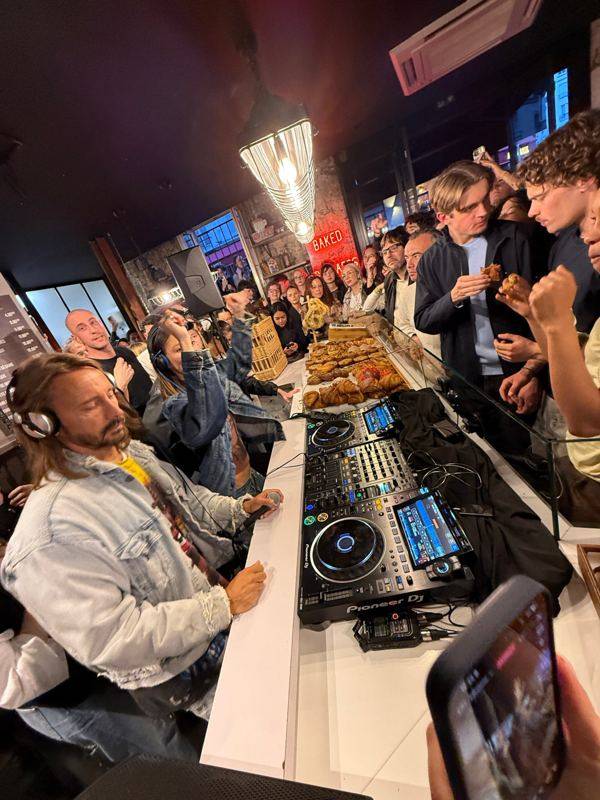 Bob Sinclar aux platines sur le comptoir d'une boulangerie, public massé autour des viennoiseries.