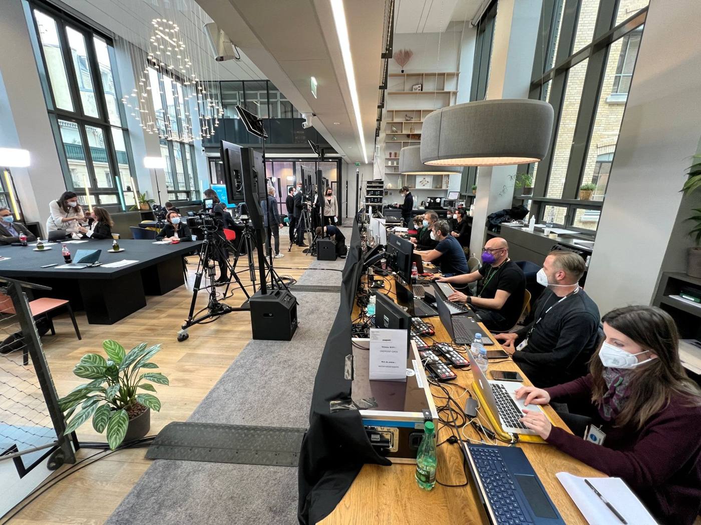 Régie vidéo installée le long d'une grande table, opérateurs devant leurs ordinateurs.
