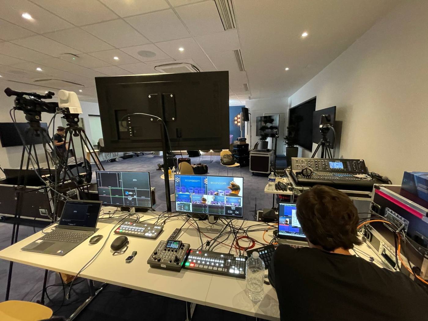 Régie vidéo : mélangeur vidéo, écrans de contrôle vMix, console de mixage numérique et ordinateurs, plateau en arrière-plan.