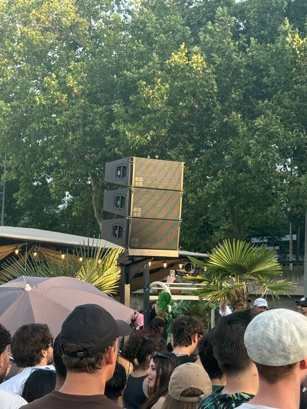 Line array et caissons de grave sur pied au bord de la Seine, péniche rouge et phare en arrière-plan.