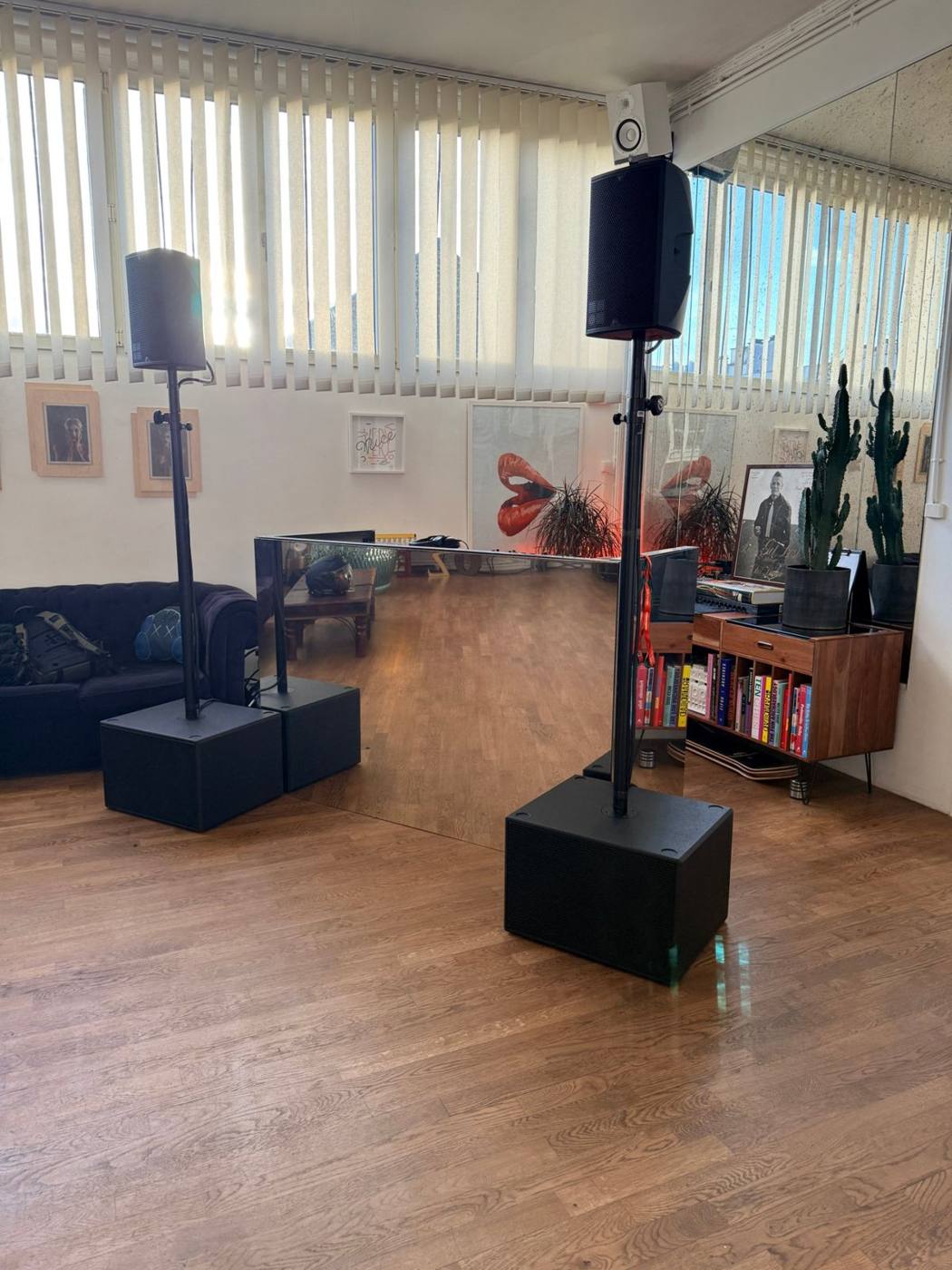 Deux enceintes sur pied avec caissons de grave dans un loft, table de DJ en miroir au centre.