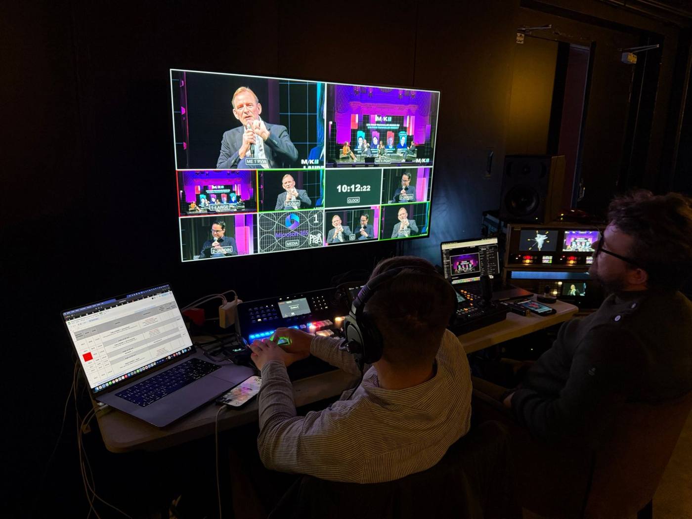 Deux régisseurs devant le grand écran multi-vue de huit caméras et le mélangeur vidéo.