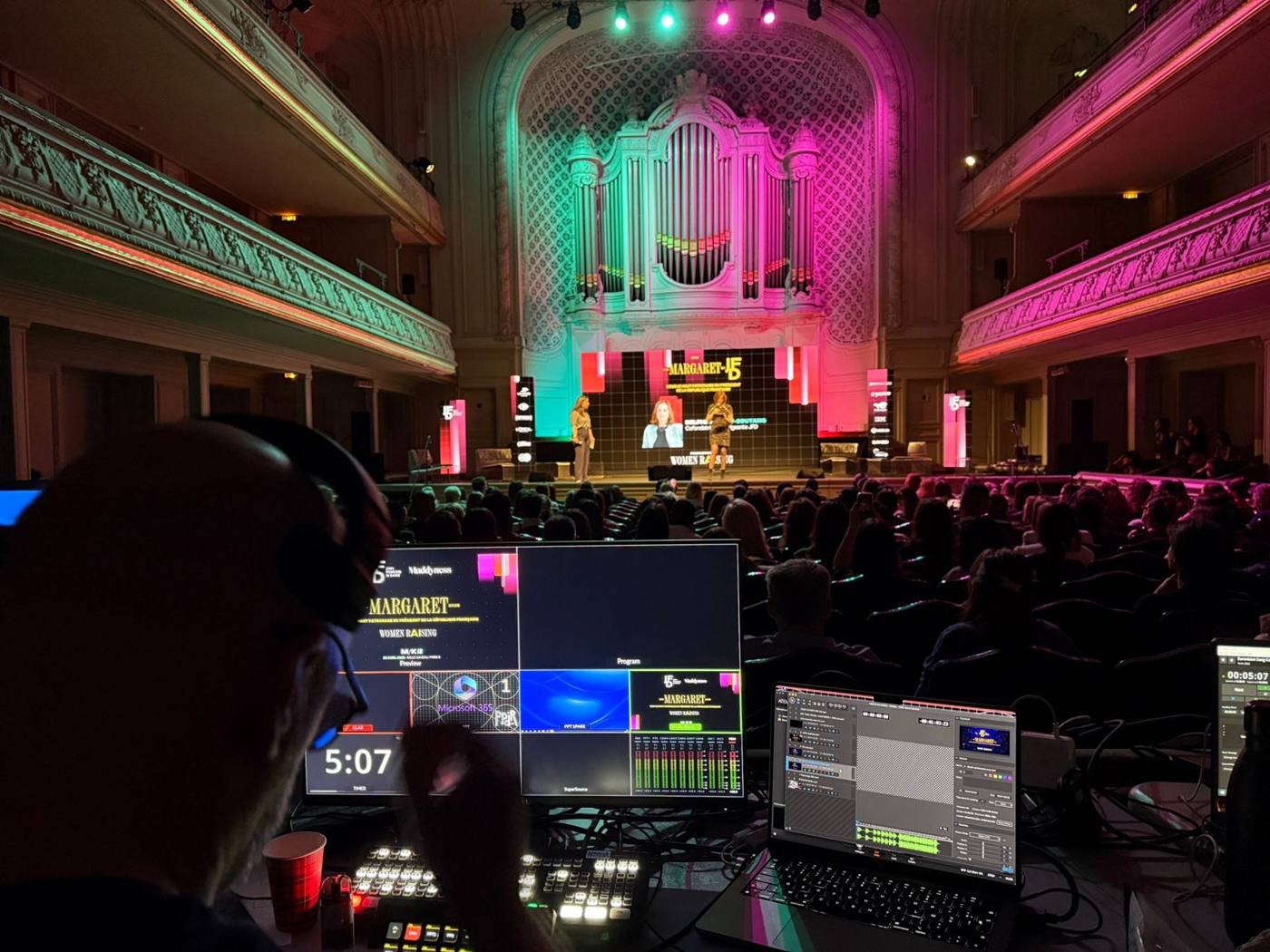 Régie vidéo au premier plan avec mélangeur et timer, remise de prix en cours sur scène devant l'orgue.