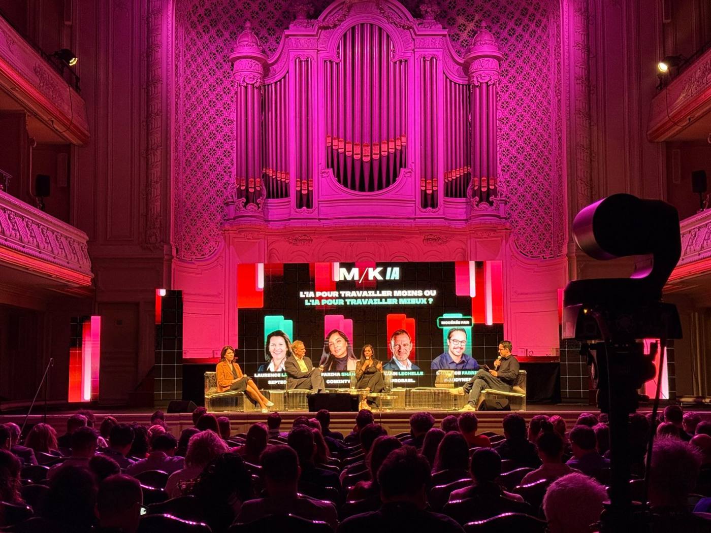 Table ronde sur scène devant l'orgue de la salle, écran M/K IA au-dessus des intervenants, public de dos.