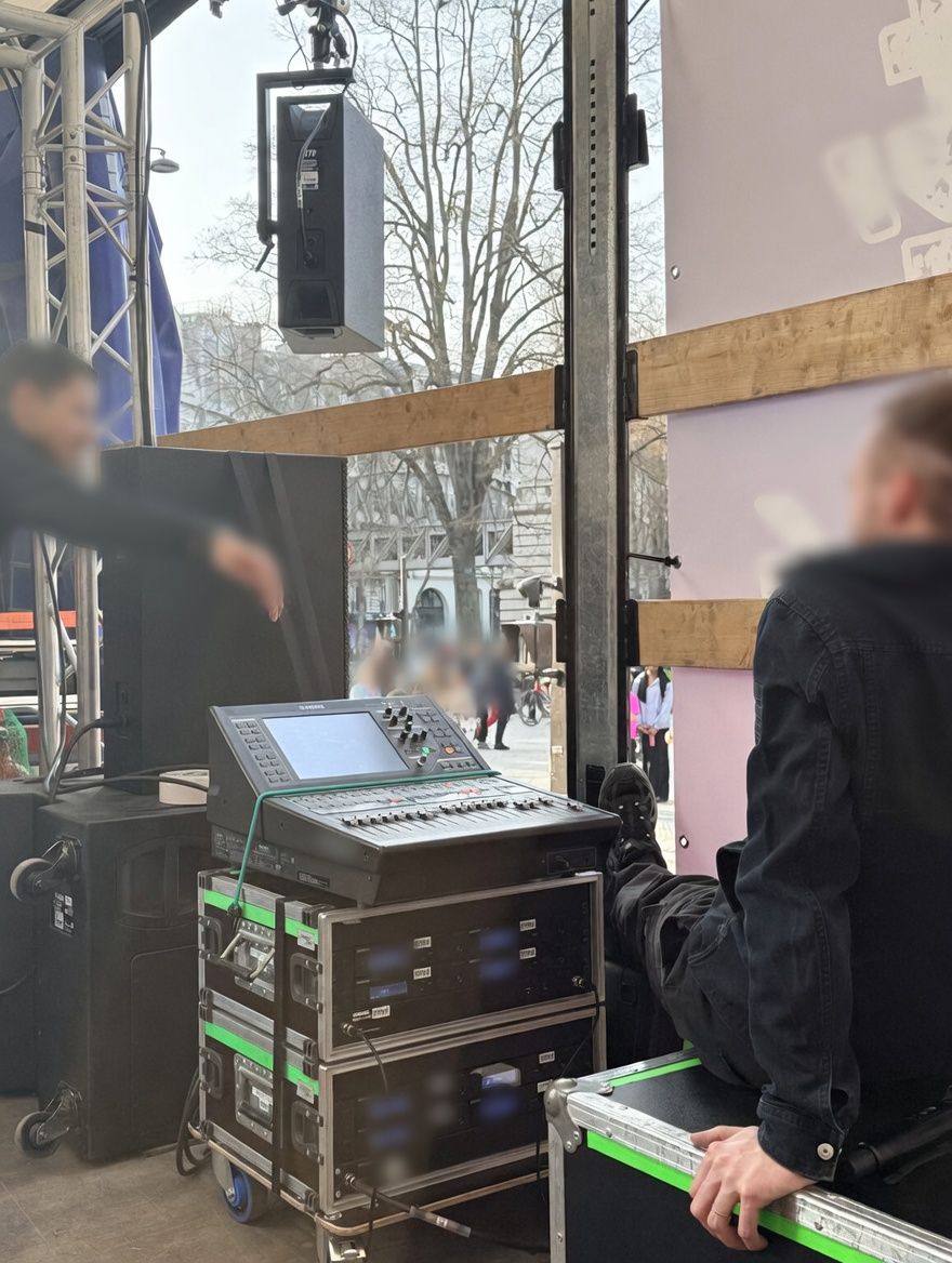 Console de mixage Yamaha et racks de micros HF posés sur le plateau du camion, avec un technicien assis à côté.