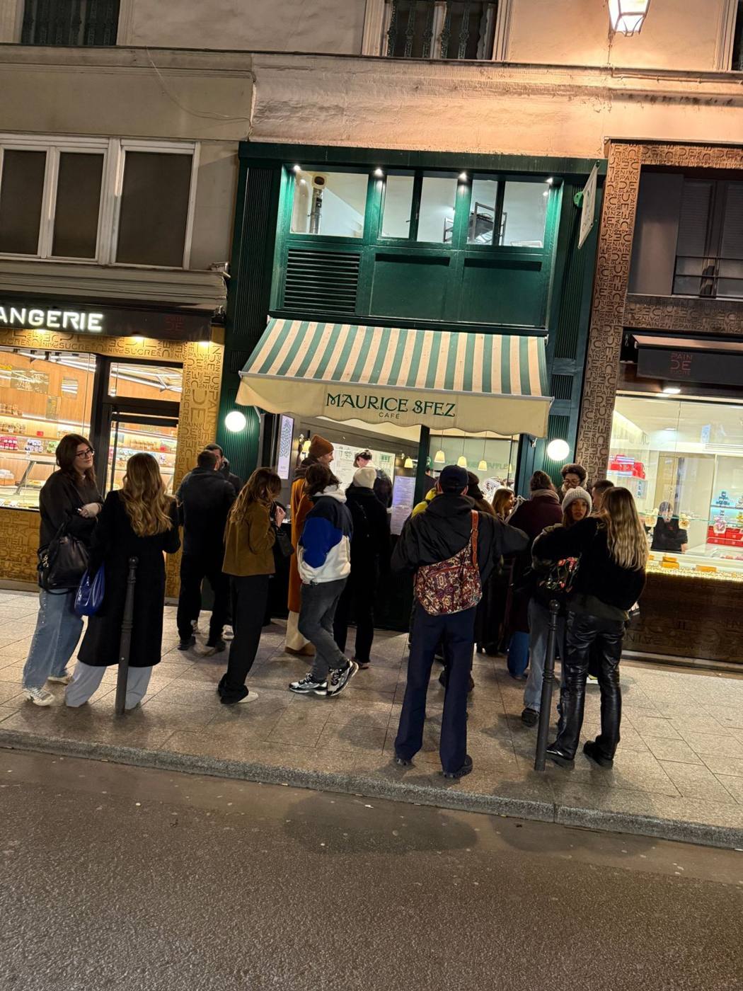 Façade du Maurice Sfez Café de nuit, store rayé vert et blanc, groupe de personnes en attente sur le trottoir.