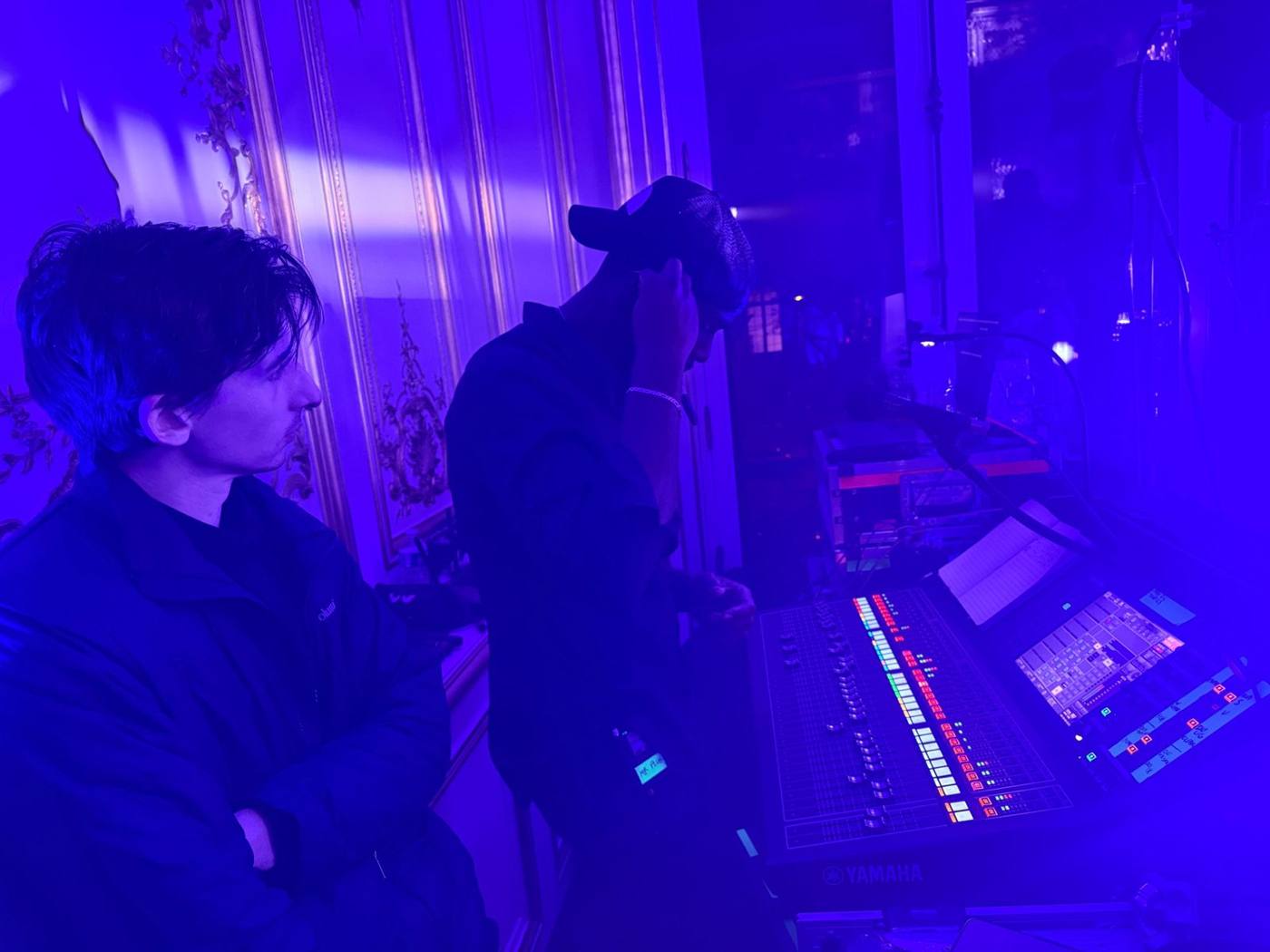 Régie son Yamaha dans une salle éclairée en bleu, deux techniciens.