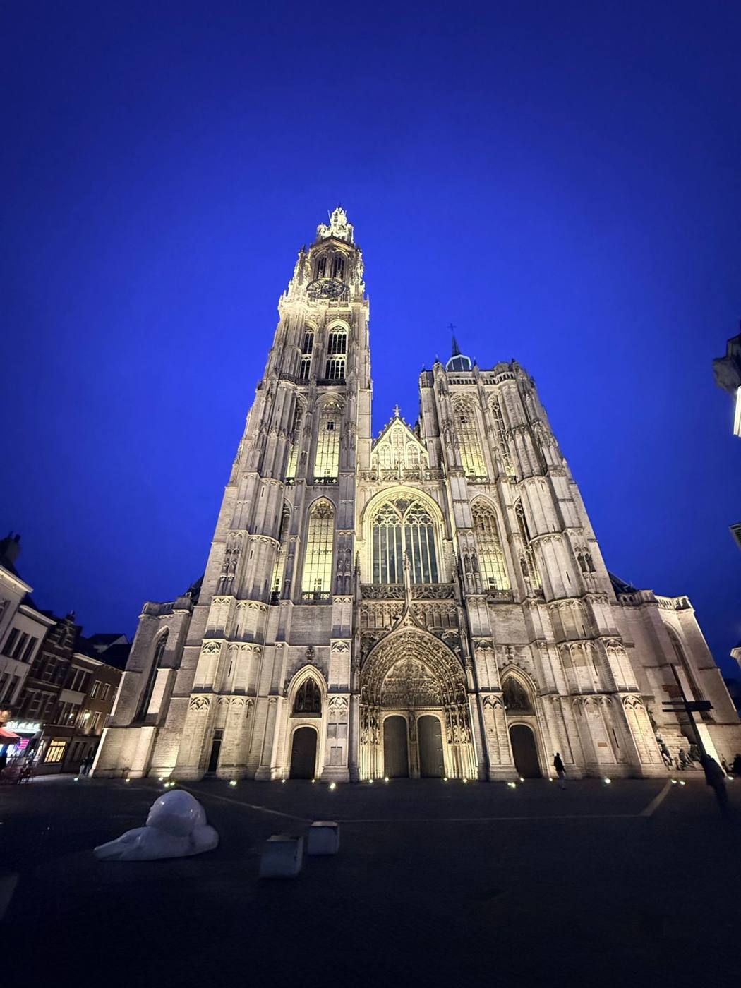 Façade d'une cathédrale gothique éclairée à la tombée de la nuit.