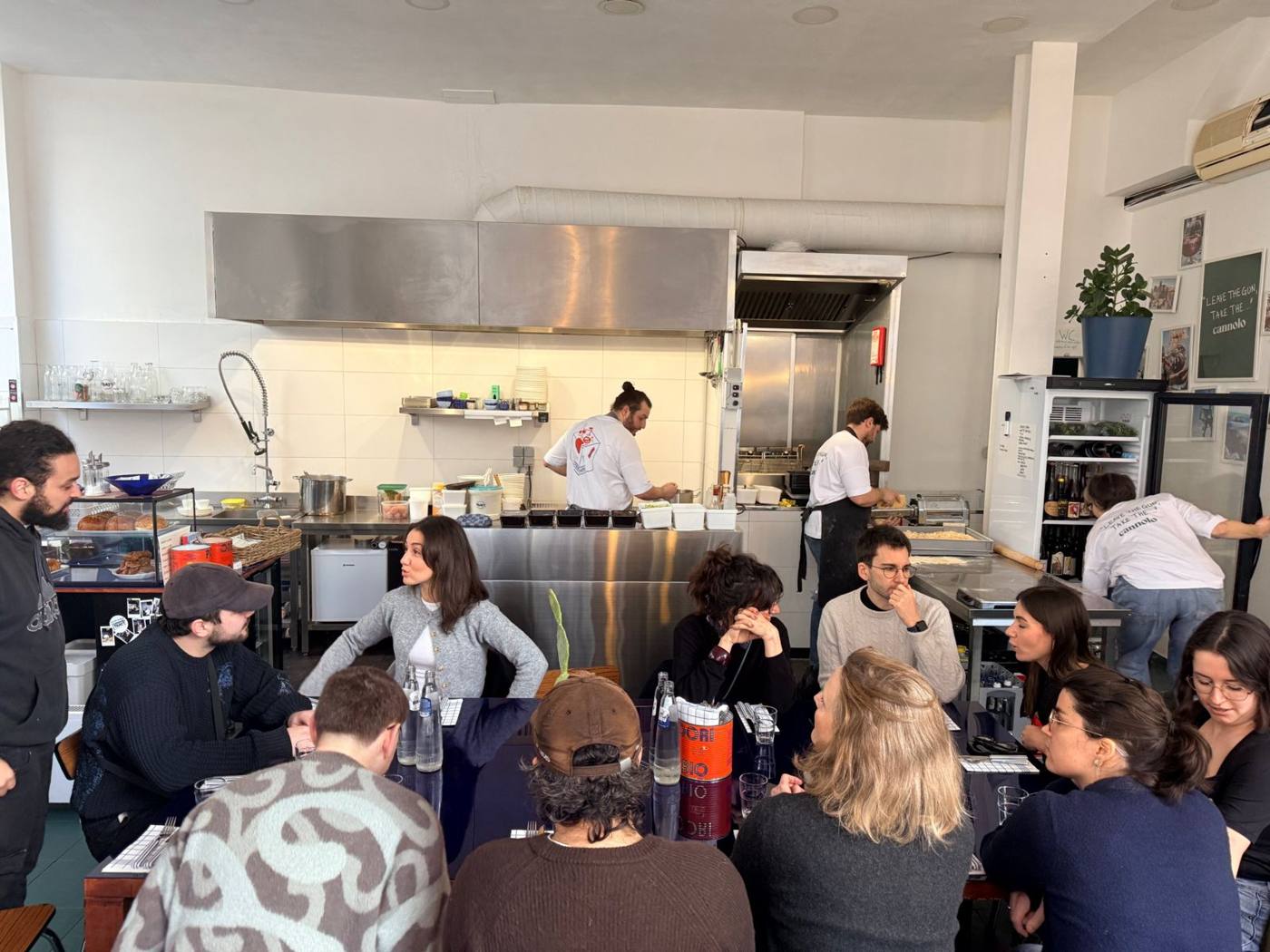 Équipe attablée devant une cuisine ouverte, cuisiniers au fond.