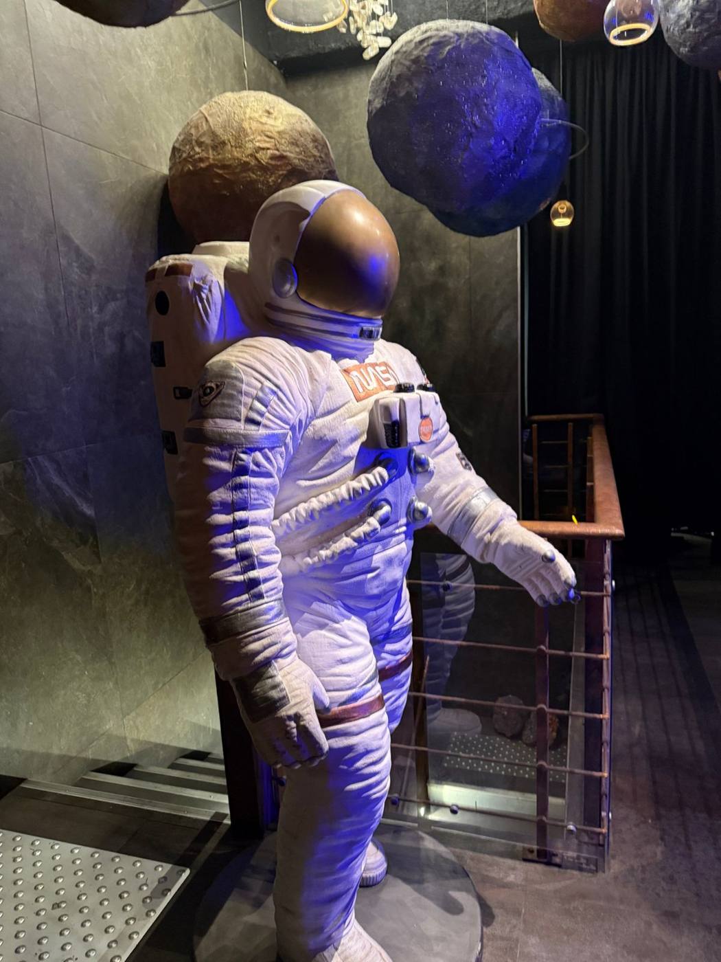 Statue d'astronaute devant un décor de planètes.