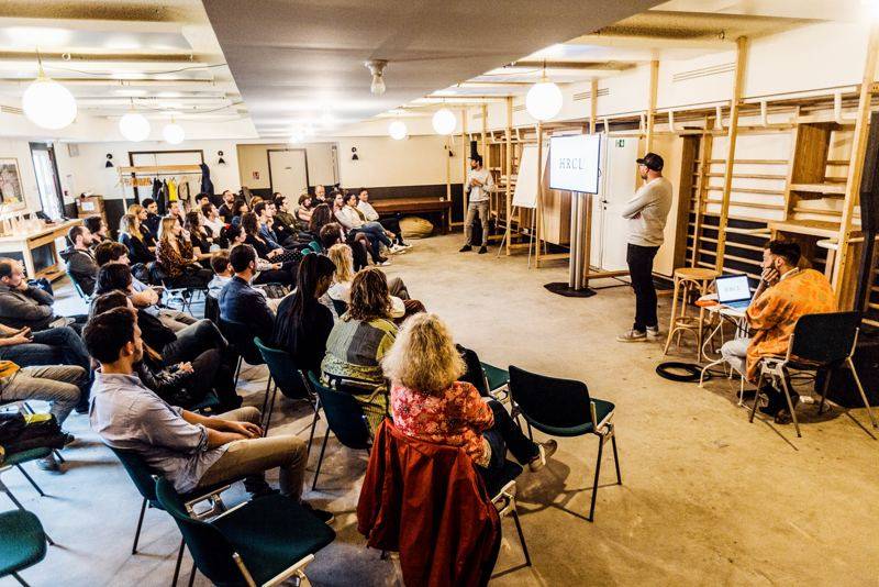 Présentation devant un écran HRCL, public assis en demi-cercle dans une salle.
