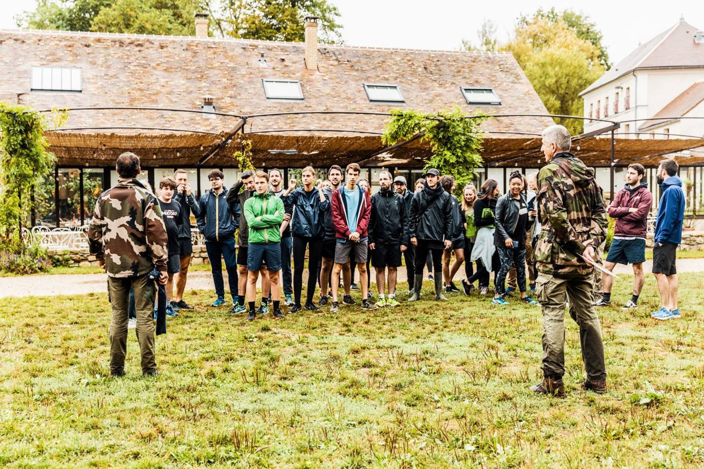 Briefing de groupe en extérieur devant un corps de ferme.