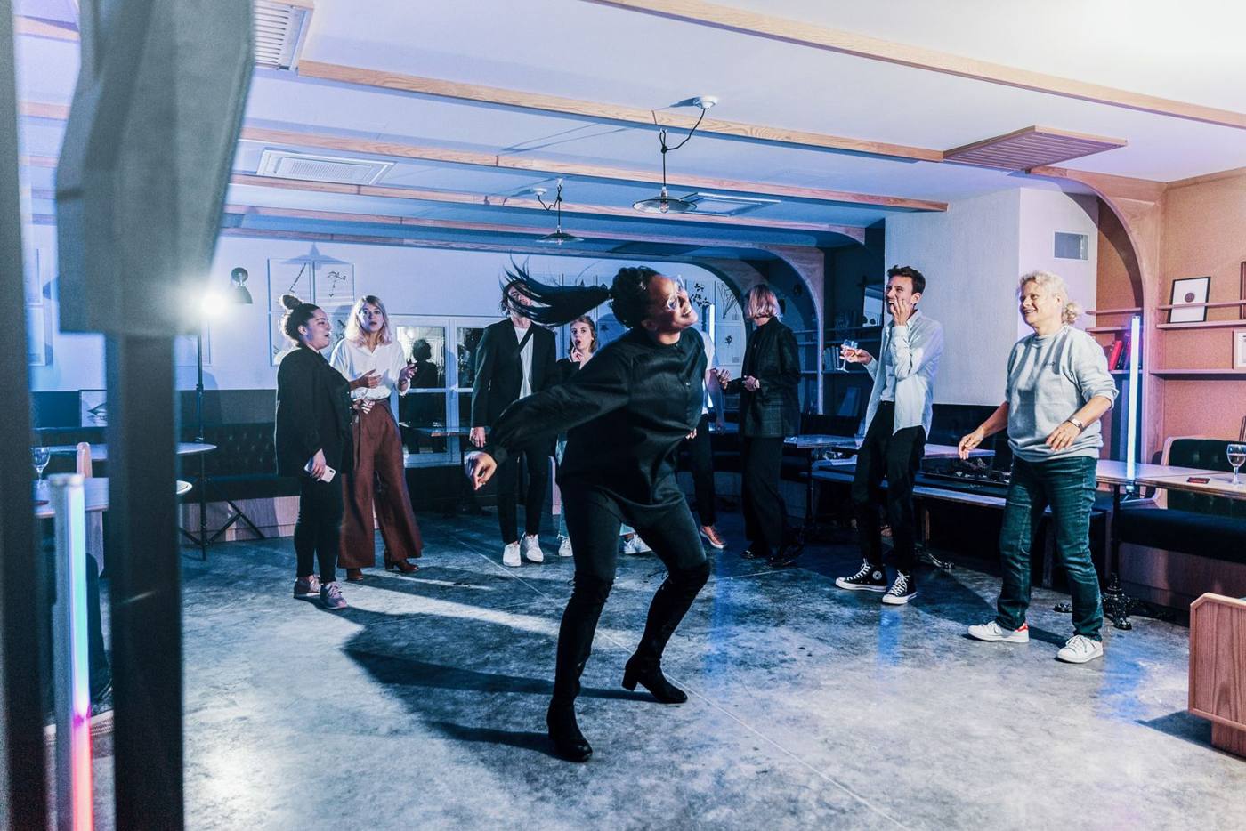Soirée : une participante danse devant les invités, éclairage bleu et rose.