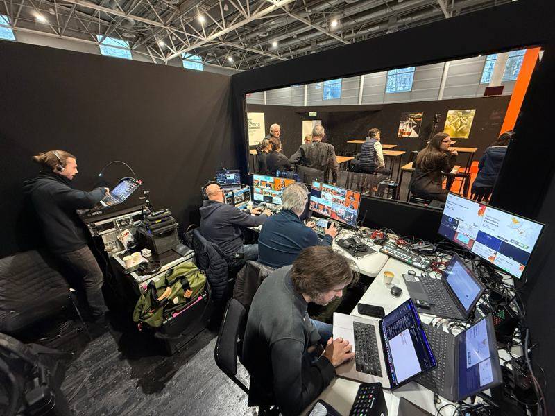 Régie vidéo et son installée derrière une vitre face à la scène orange, écrans de contrôle et console Yamaha.