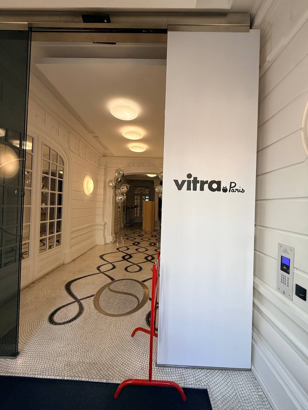 Entrée du showroom, panneau « Vitra Paris » et hall en mosaïque au fond.
